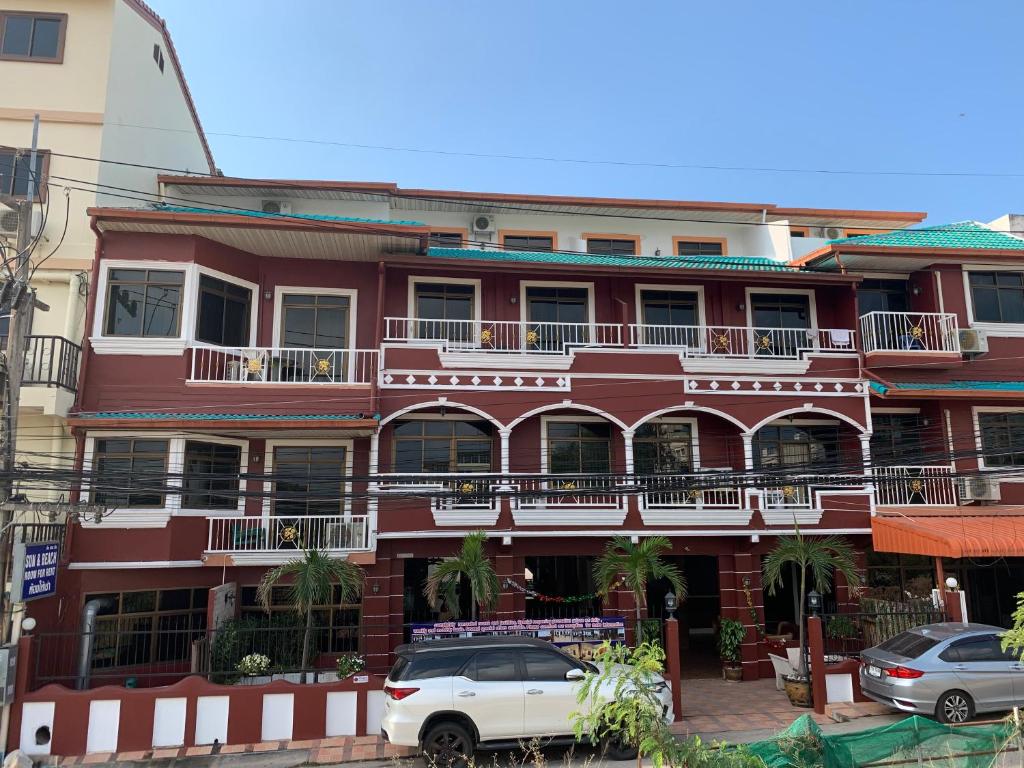 a red building with cars parked in front of it at Sun and beach hotel in Pattaya South