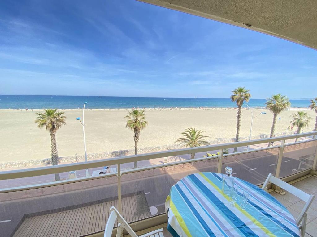 un balcon avec vue sur la plage et les palmiers dans l'établissement Grand 2 pièces avec terrasse face à la mer à Canet-en-Roussillon - FR-1-833-1, à Canet
