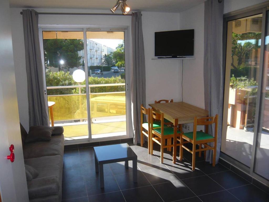 un salon avec une table, des chaises et une télévision dans l'établissement Studio Cabine avec Terrasse Spacieuse à 300m de la Plage - FR-1-833-28, à Canet