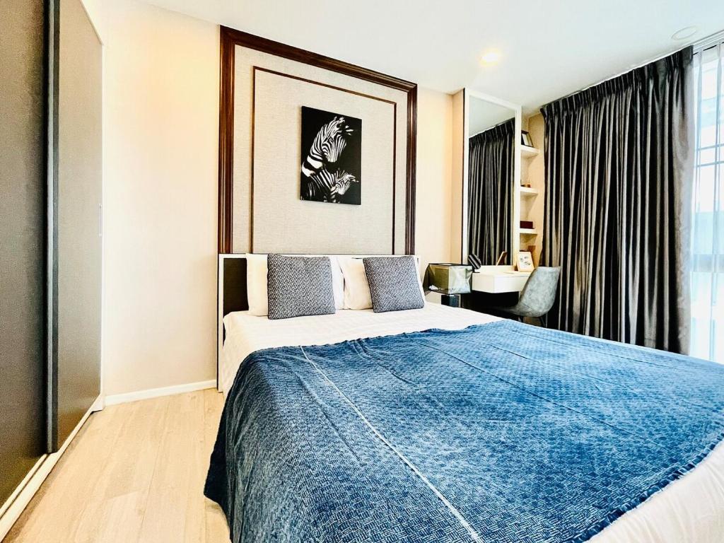 a bedroom with a large bed with a blue blanket at Best Quiet Cozy Palm Springs Condo in Center Nimma in Chiang Mai