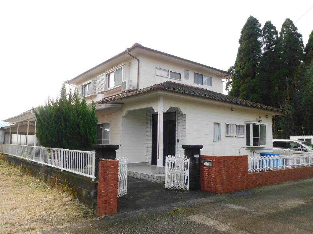 a white house with a white fence in front of it at えびのペンション in Ebino