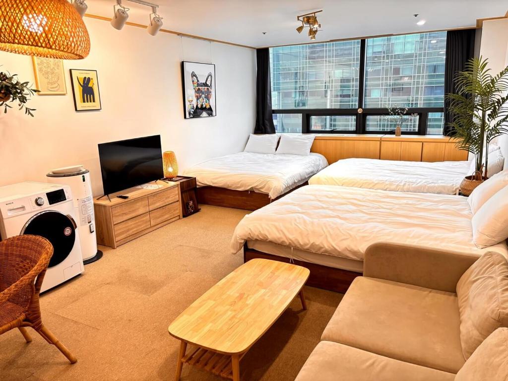 a room with two beds and a couch and a tv at 18 Hongik Univ Best location city view in Seoul