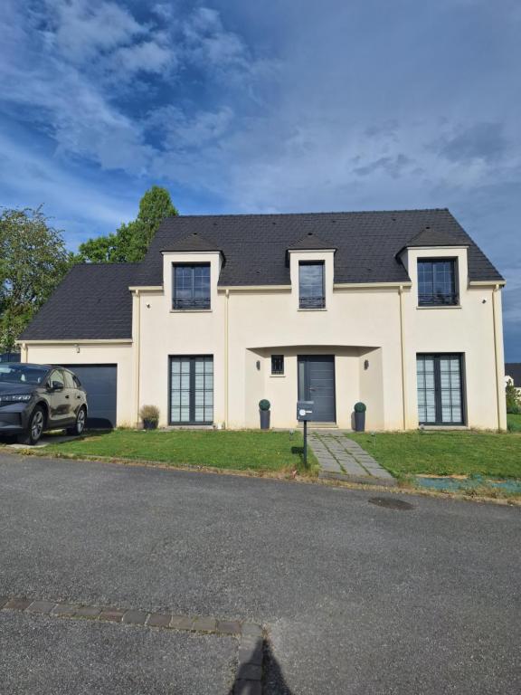 a white house with a car parked in front of it at Belle Maison Récente in Neauphle-le-Château