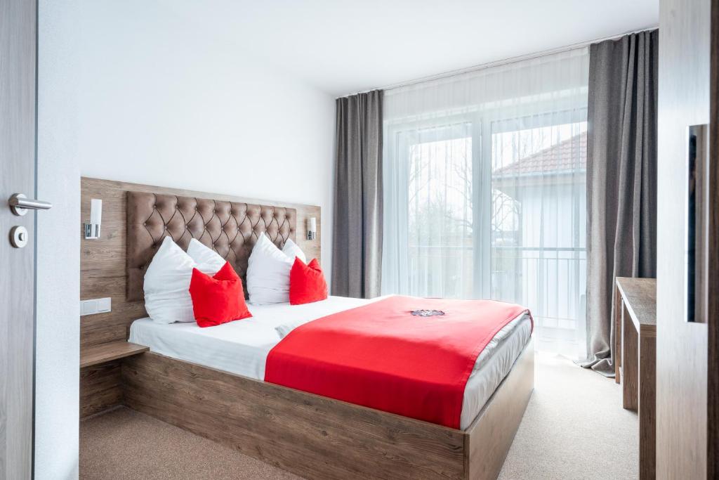 ein Schlafzimmer mit einem Bett mit roten Kissen und einem Fenster in der Unterkunft B&S Hotel in Weißenhorn