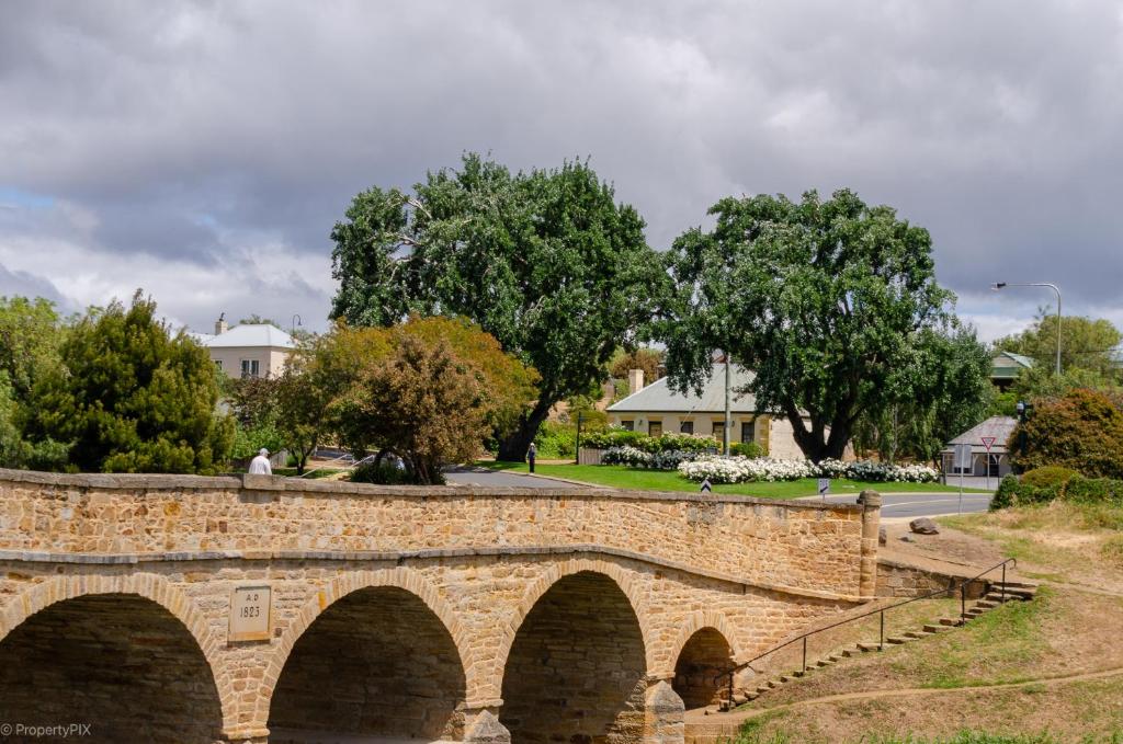 eine Brücke über einen Fluss mit einer Person darauf in der Unterkunft BRIDGE COTTAGES Sargeants & Armoury Cottages 1823 - HISTORY & CHARM in Richmond