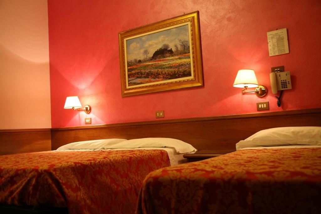 a hotel room with two beds and a painting on the wall at Hotel San Pellegrino in Spilamberto