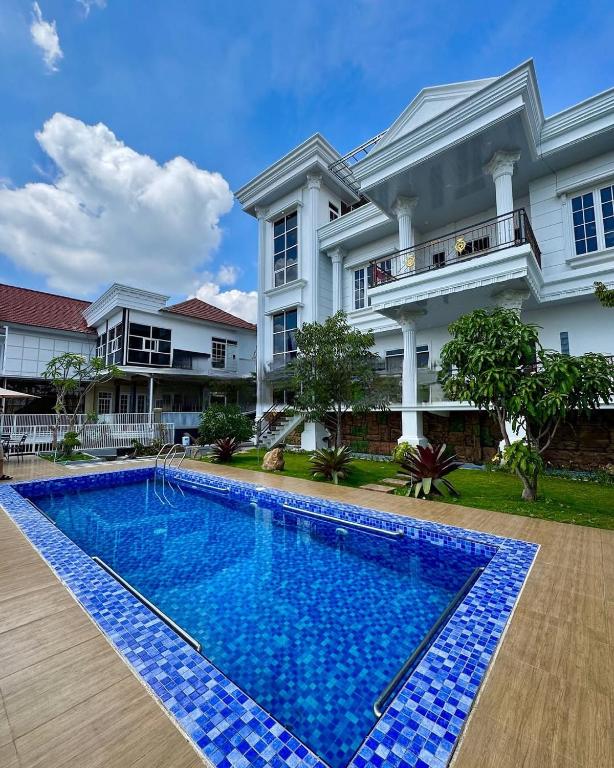 a villa with a swimming pool in front of a house at Villa putih 10 kamar in Tlekung