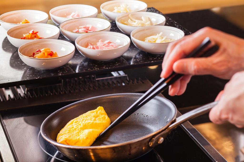a person cooking food in a pan on a stove at Shin Yokohama Prince Hotel in Yokohama