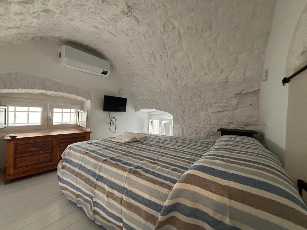Un dormitorio con una cama y una pared de piedra. en Casetta Arco Casavola, en Martina Franca