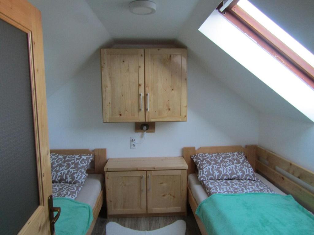 a attic room with two beds and a cabinet at Hegyi Vendégház in Vărşag