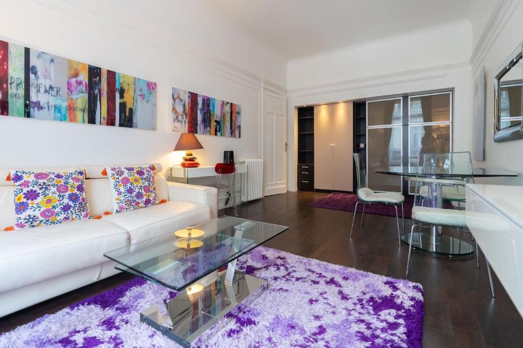un salon avec un canapé blanc et une table en verre dans l'établissement Champs Elysées Apartment, à Paris