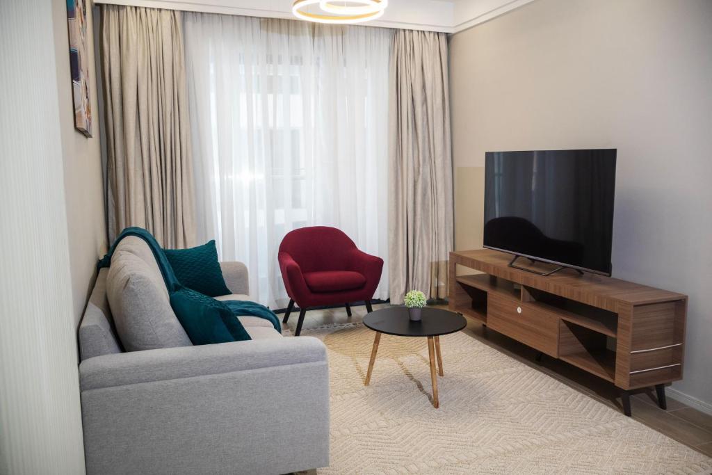 a living room with a couch and a flat screen tv at Cozy & Luxury Apartment Lavington, Nairobi in Nairobi