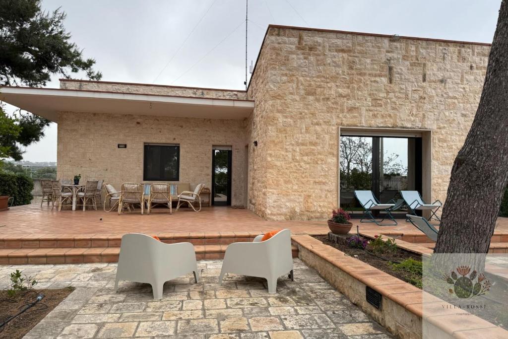 a brick house with a patio and white chairs at Villa Rossi in Polignano a Mare