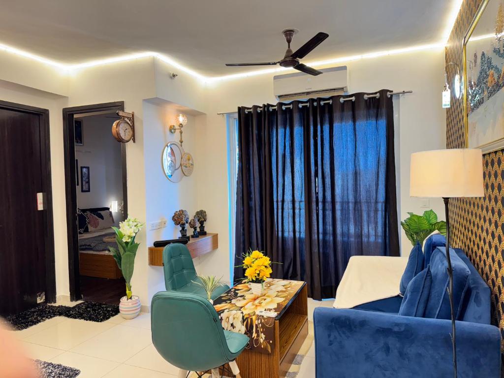a living room with blue chairs and a table at Harmony Heights By Royal Rooms in Noida