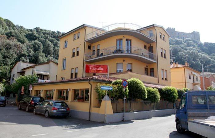 un grand bâtiment jaune avec des voitures garées devant lui dans l'établissement Albergo Rossella, à Castiglione della Pescaia