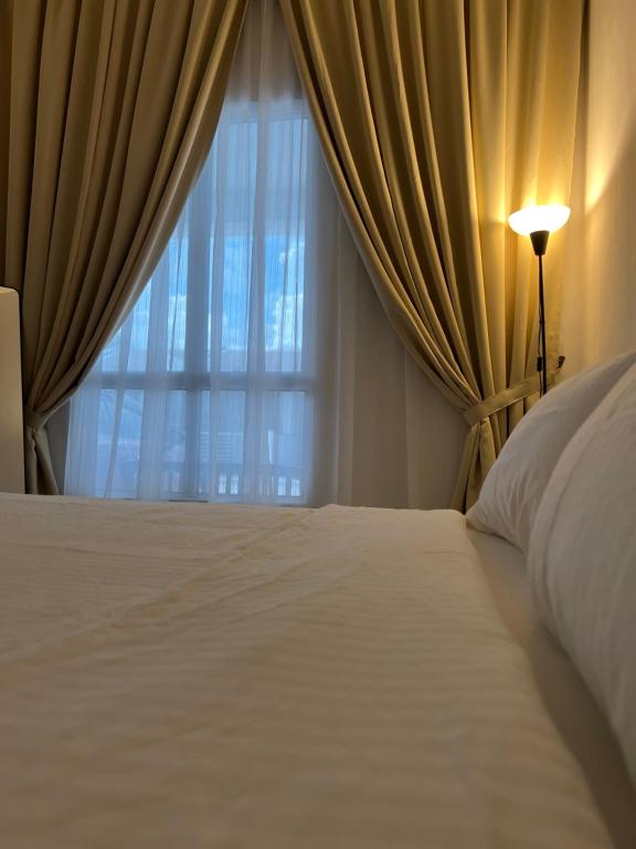 a bedroom with a white bed and a window at Rumavin Homestay, Seremban in Seremban