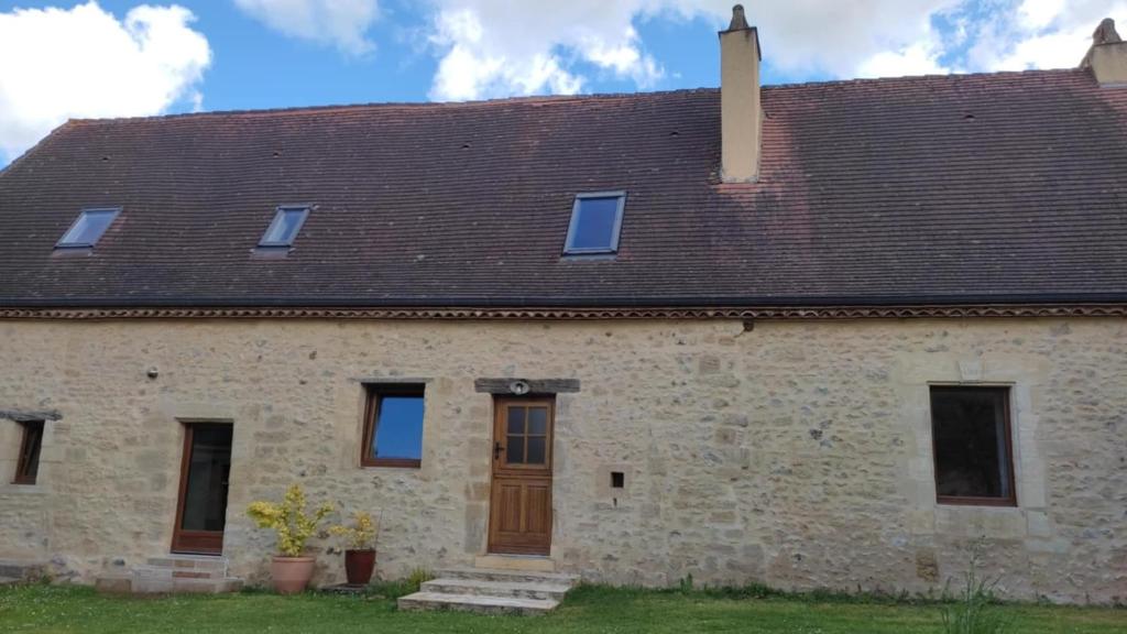 une ancienne maison en pierre avec un toit brun dans l'établissement Gite la lauzerie, à Mauzens-et-Miremont