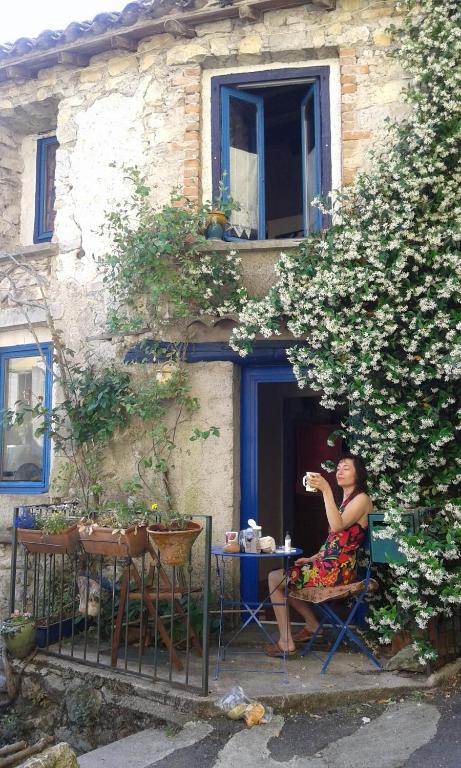 une femme assise sur une chaise devant un bâtiment dans l'établissement Maisonnette typique, coeur du village médiéval de Sauve, à Sauve