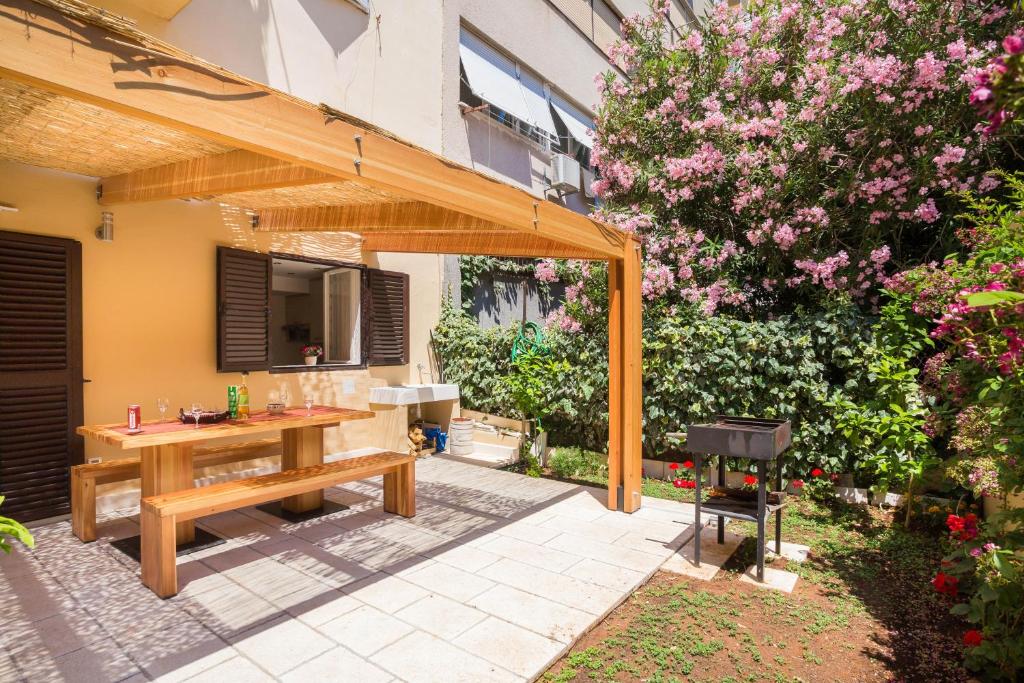 a patio with a wooden table in a garden at Apartment Dora in Split