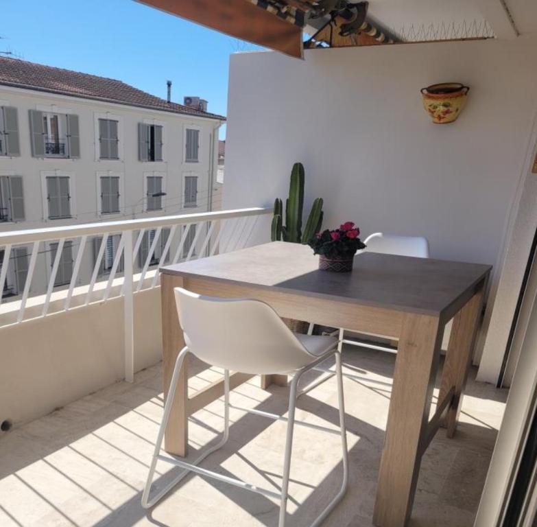 une table et des chaises en bois sur un balcon dans l'établissement Center Cannes Montfleury, à Cannes