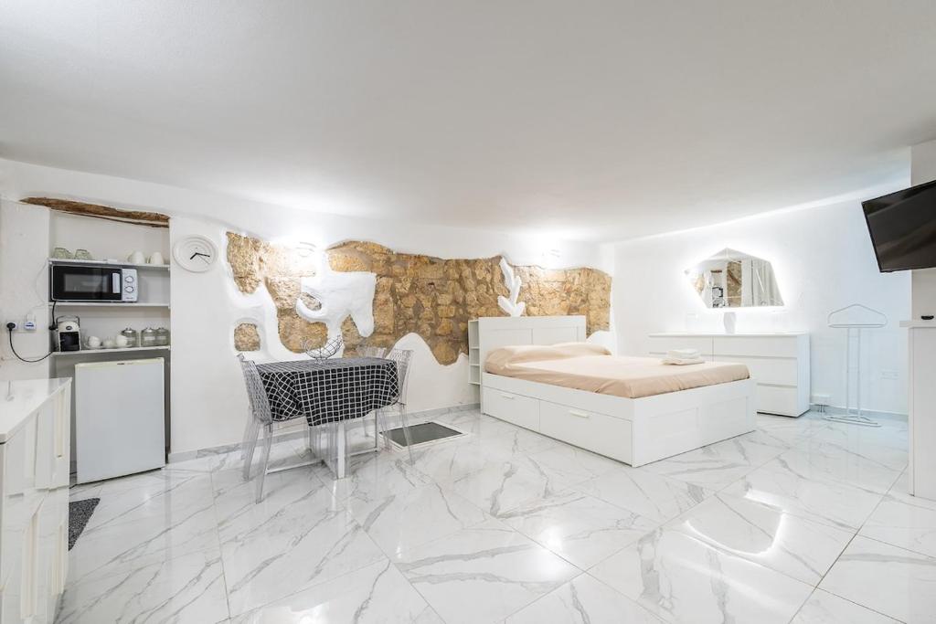 a white room with a bed and a kitchen at Family JC in Cagliari