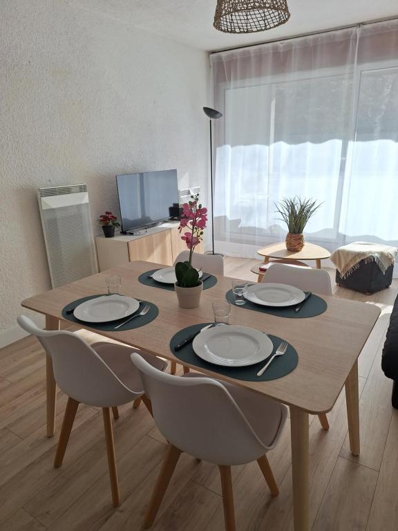 - une table à manger avec des assiettes et des chaises dans le salon dans l'établissement Appartement St Lary Soulan village - Classé 3 étoiles et labelisé - WIFI inclus, à Saint-Lary-Soulan
