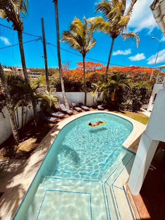 a person swimming in a swimming pool with palm trees at Mont Choisy Lodge 7 Rooms, Large Pool, 2 Min Walk to Beach in Grand-Baie
