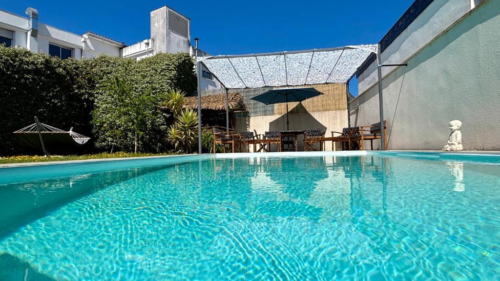 - une piscine bleue avec une table et un parasol dans l'établissement Villa TIKI BAR piscine chauffée 4 chambres, à Labenne