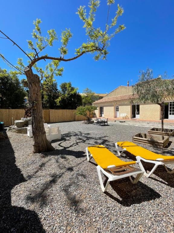 2 chaises longues jaunes assises à côté d'un arbre dans l'établissement Villa Manaha - 6pers - clim - proche plage, à Lapalme
