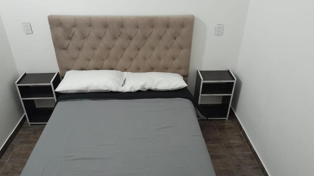 a small bedroom with a bed with two night stands at hospedaje monte grande in Monte Grande