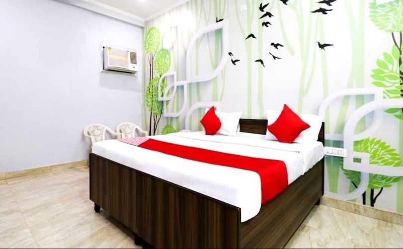 a bedroom with a bed with red pillows and birds on the wall at Hotel O Smart City Guest House in Ballabgarh