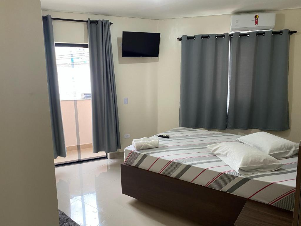 a bedroom with a bed with a window and a television at Hotel Novo Apúlia in Sao Paulo