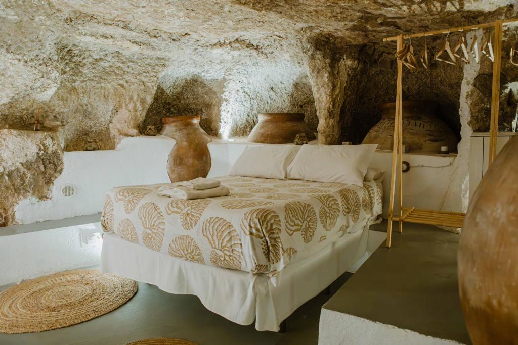 una camera da letto con un letto in una stanza di pietra di Casa Cueva Las Tinajas de Naya ad Alcalá del Júcar