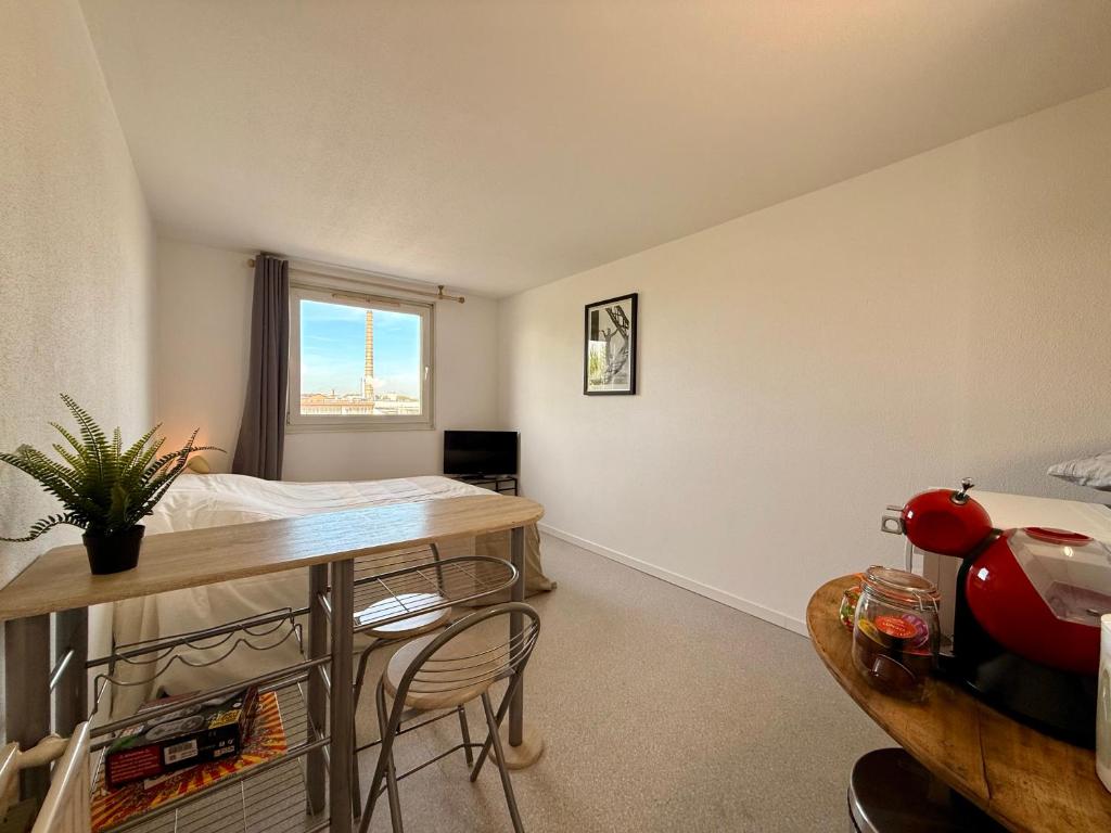 une chambre avec un lit, une table et des chaises dans l'établissement Studio Strasbourg Proche Tram, à Strasbourg
