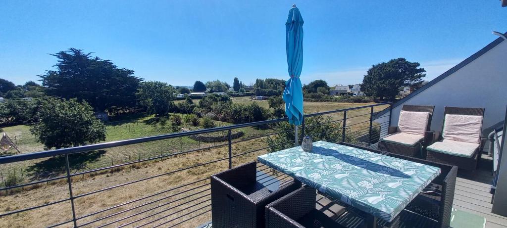 une table et des chaises sur un balcon avec un parasol dans l'établissement Bel appartement avec terrasse et sa petite vue mer Kerroc'h, à Ploemeur
