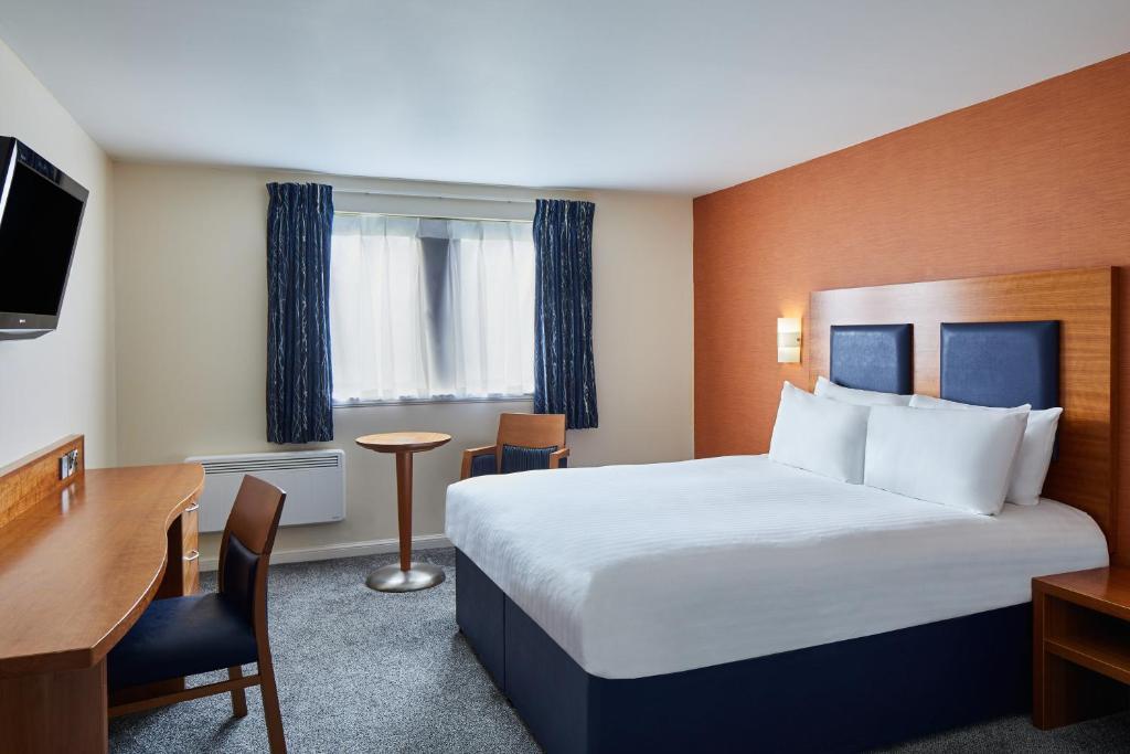 a hotel room with a large bed and a desk at Leonardo Inn Aberdeen Airport in Dyce
