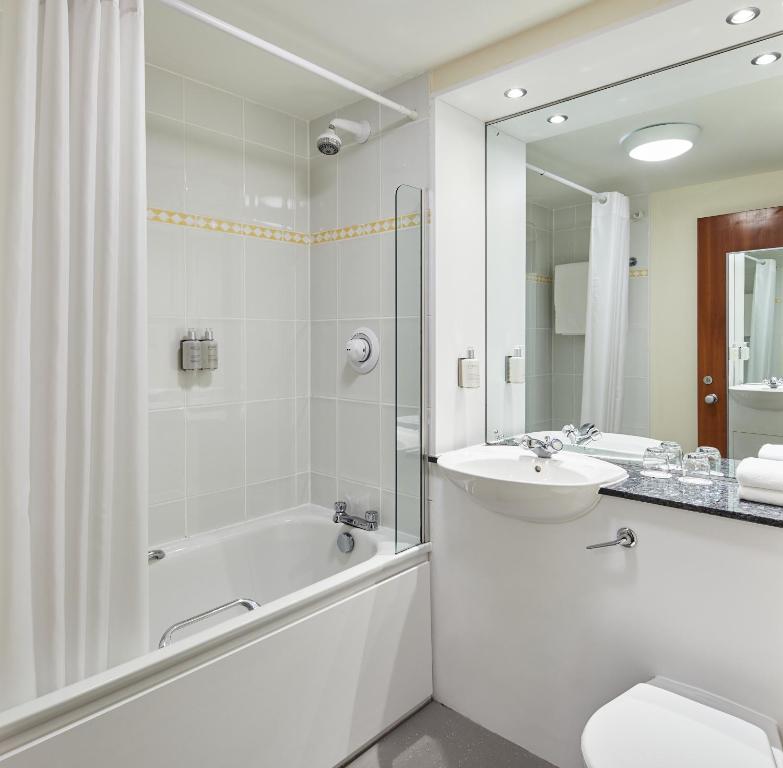 a white bathroom with a tub and a sink and a bath tubermott at Leonardo Inn Aberdeen Airport in Dyce