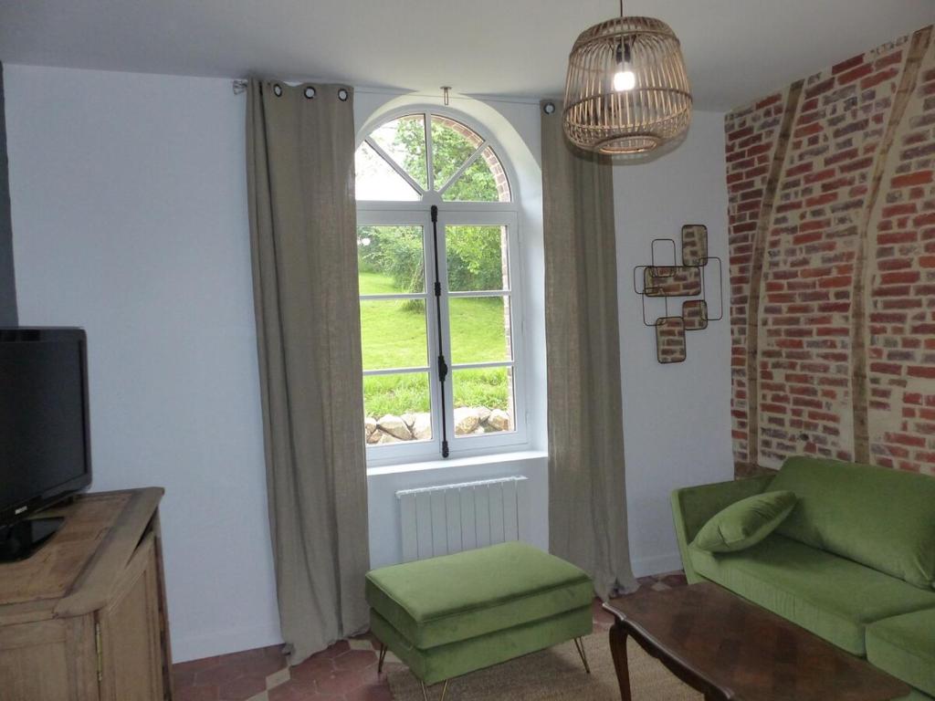 een woonkamer met een raam en een groene stoel bij Passage du Marché in Blainville-Crevon