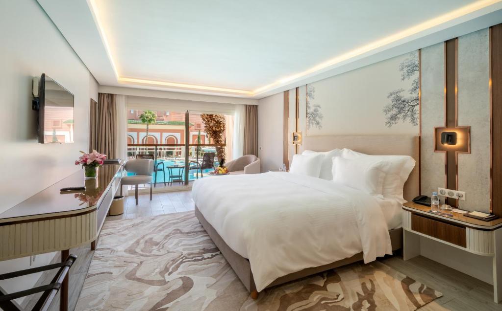 a hotel room with a large bed and a desk at Savoy Le Grand Hotel Marrakech in Marrakesh