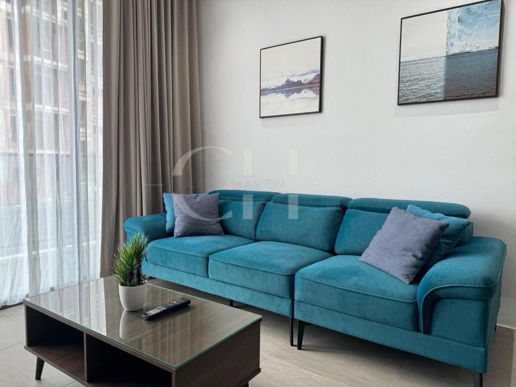 a blue couch in a living room with a table at Kuching Rex 2 bedrooms for 4 pax in Kuching