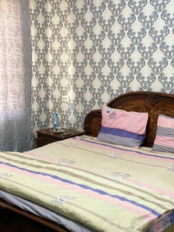 a bed with pink and purple pillows in a bedroom at Aile Bukhara in Bukhara