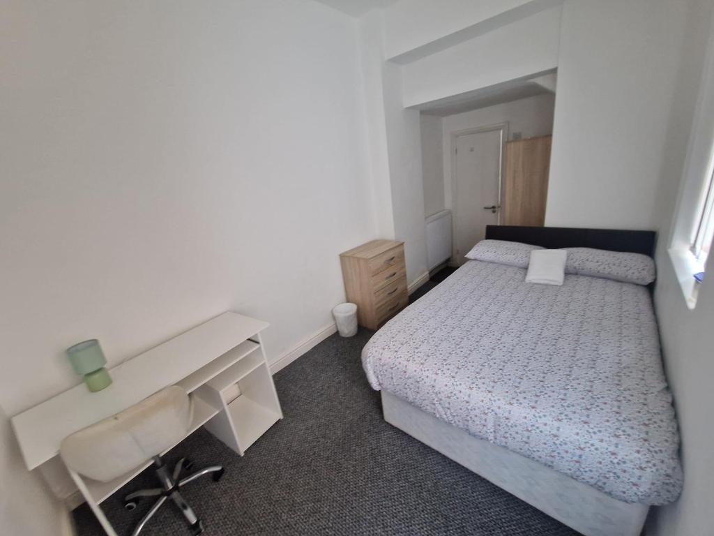 a small bedroom with a bed and a desk at Shelton Old Road Guest house in Stoke on Trent
