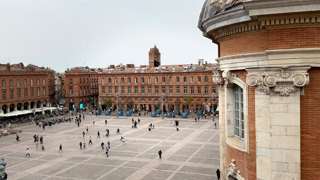 Un groupe de personnes marchant sur une place devant un bâtiment dans l'établissement Beautiful flat on Capitole Place, à Toulouse