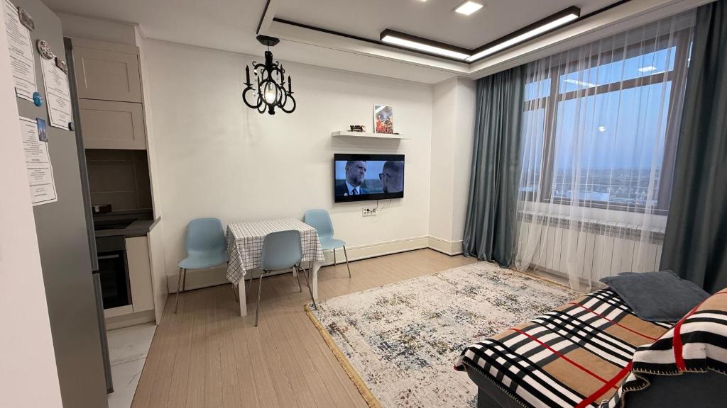Una sala de estar con una mesa y sillas y un televisor. en ЖК Highvill Ishim D1, en Astana