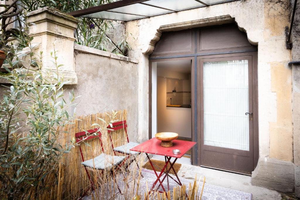 une table rouge et des chaises devant une porte dans l'établissement Salut Le Petit Gite, à Carcassonne