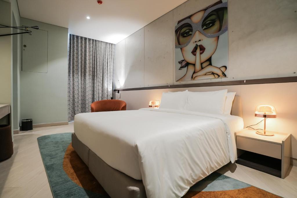コロンボにあるSeSaya Poshtel & Bistroの大きなベッドと女性の絵画が備わるベッドルーム