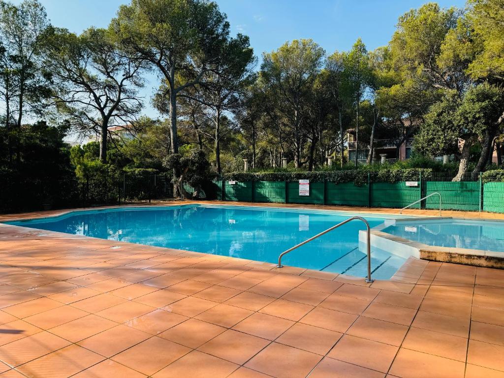 une piscine vide avec un sol carrelé et des arbres dans l'établissement Studio climatisé avec piscine et parking privé, à Fréjus