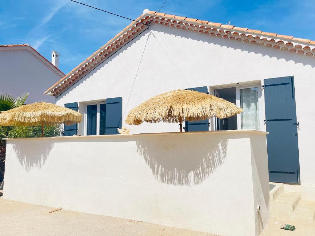 une maison blanche avec deux parasols en paille dans l'établissement Beau 2 pièces emplacement n 1 proche de la mer, à Fréjus