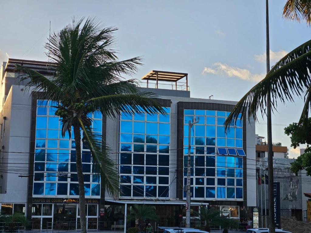 a building with a palm tree in front of it at Apto 515 - Seu Refúgio na Praia - Nobile Hotel in João Pessoa