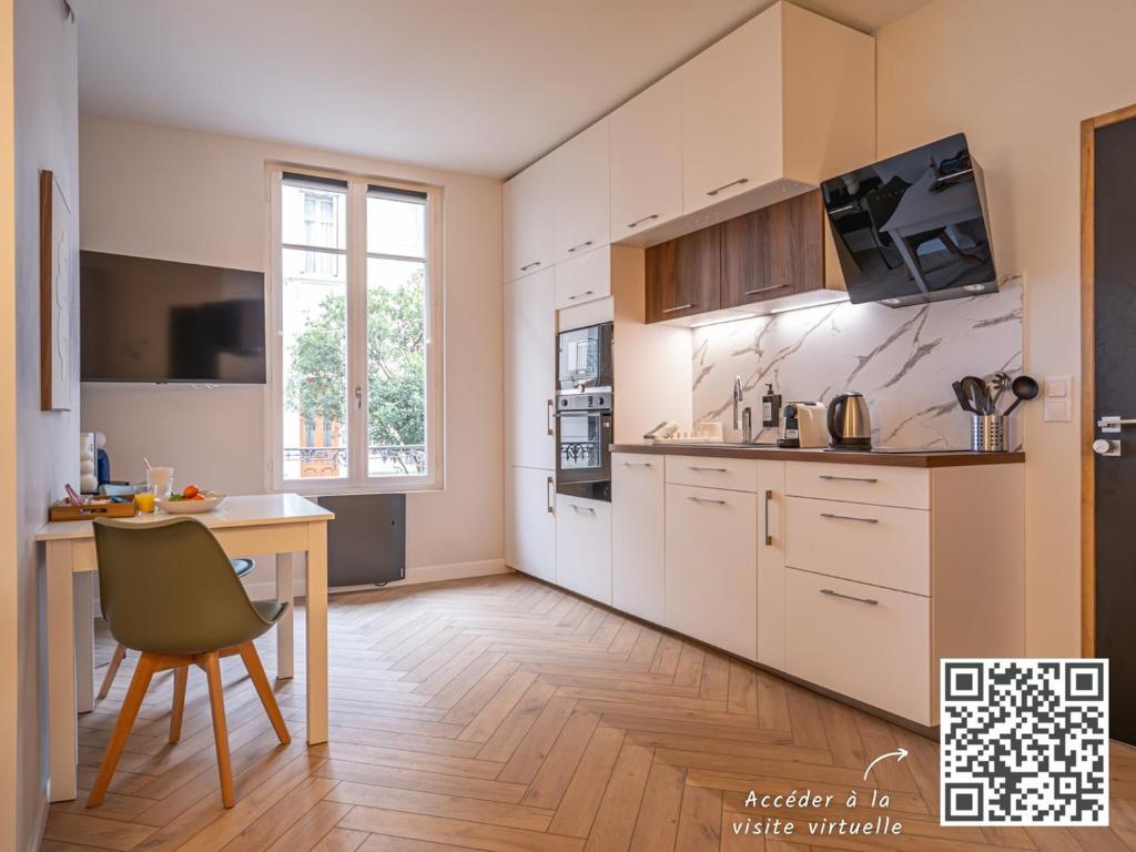 une cuisine avec des placards blancs et une table avec une chaise dans l'établissement OIQIA • Palace Hôtel • N°1, à Tours